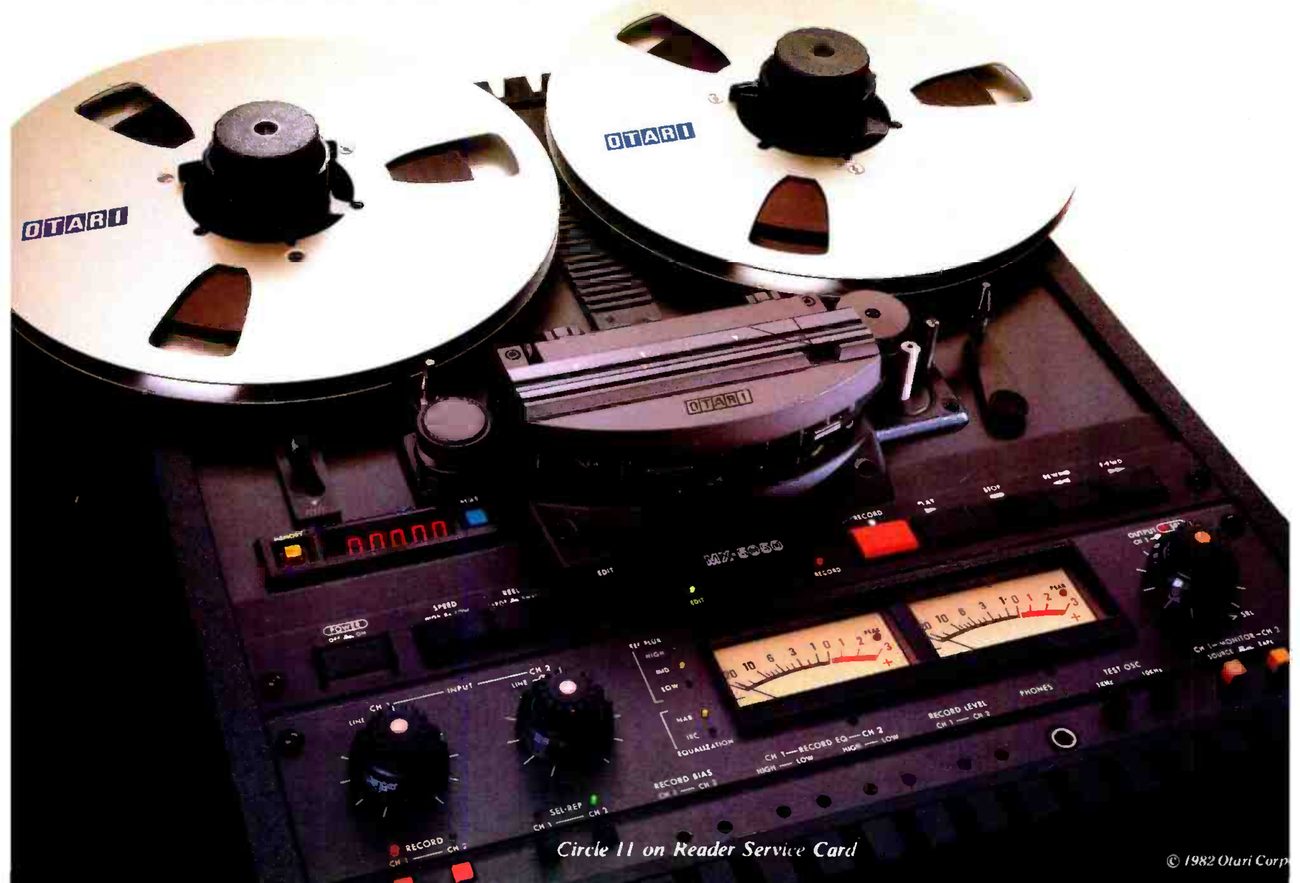 The MX-5050B-II photographed close up from above: two large reels with OTARI printed on the flanges, the head assembly under its cover with the OTARI badge, the red five-digit LED counter at left, the transport buttons with a red RECORD key, a pair of VU meters with red peak segments, and the input, record-level and output knobs along the electronics panel below.