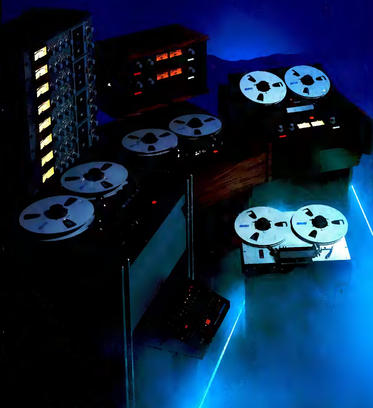 A group of Otari machines lit blue in a dark studio: a tall rack of eight-track electronics with a row of lit meters at the left, several reel-to-reel transports in wooden consoles and cabinets, an electronics unit with two rows of orange-lit meters behind them, and a transport with two reels at front right.