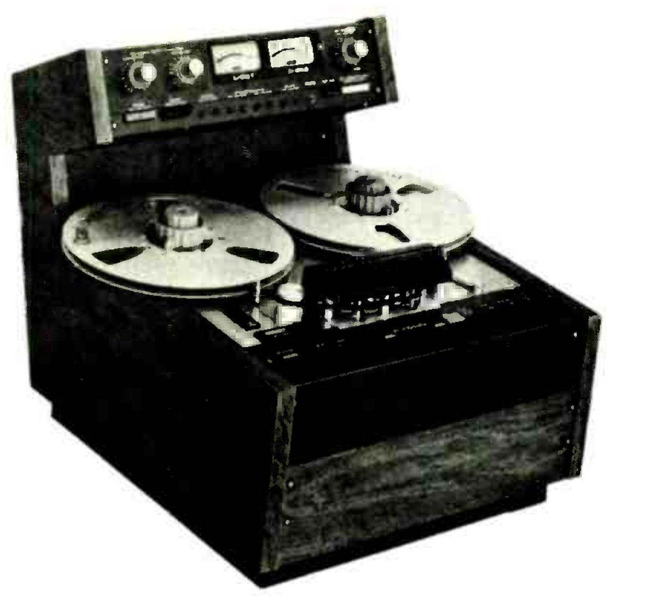 The Mark II photographed from a high three-quarter angle in a wooden floor cabinet: two reels on the transport, the head assembly under its cover, and the electronics in a separate raised housing behind the transport with two VU meters between level knobs.