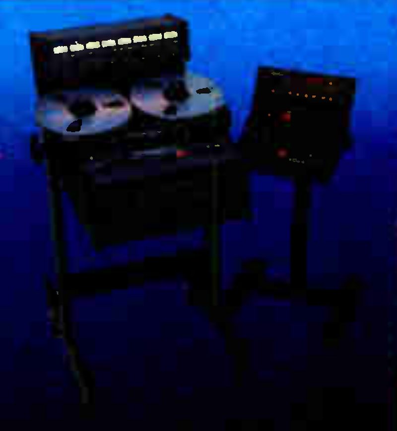 The MARK III/8 on its console stand against a blue ground: a meter bridge with a row of eight lit meters above two reels, and a remote unit on a pedestal to the right, its red indicators lit.
