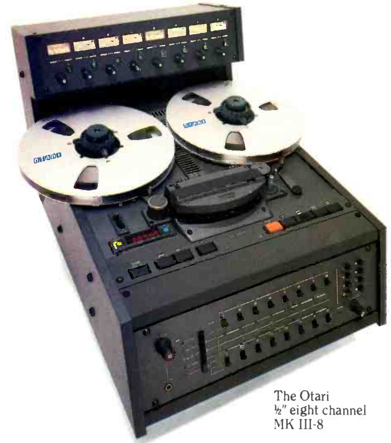 The Mark III-8 photographed from a high three-quarter angle: the eight-channel meter bridge with its level controls on top, two large reels with OTARI on the flanges, the head block under its cover, the tape counter and transport buttons, and the eight-channel electronics panel below.