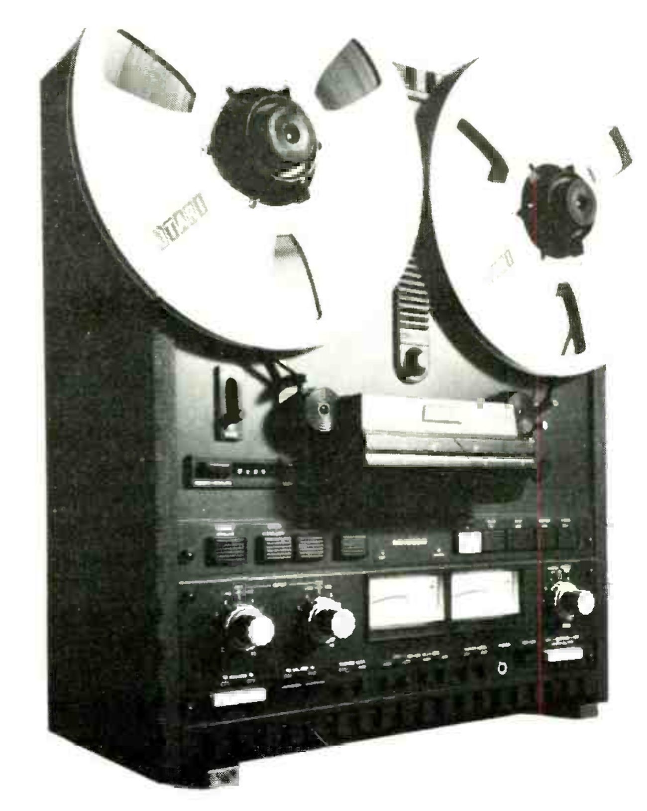 The MX-5050-B photographed from a three-quarter angle with a large Otari reel on each hub, the hinged head cover and splicing block below the reels, the row of push buttons across the transport, and the two VU meters between the input and output level knobs on the electronics panel.