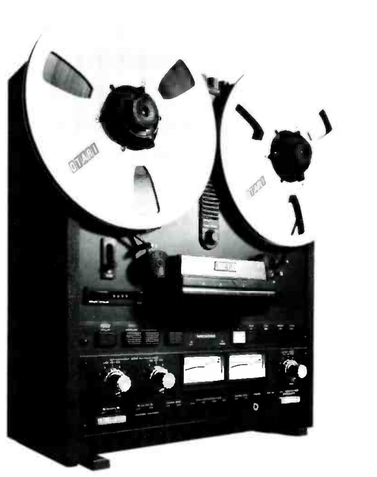 The MX-5050-B photographed from a three-quarter angle: two large reels with OTARI printed on the flanges, the head assembly under its cover, the transport pushbuttons, and the electronics panel below with two VU meters flanked by level knobs, the dark cabinet side standing on two feet.