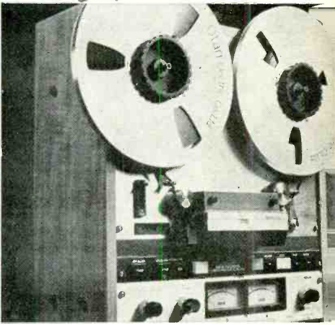 The MX 5050 photographed close up from the front: two large reels, Otari printed on the left-hand flange, the head assembly and splicing block under the reels, the transport push buttons, and two VU meters flanked by level knobs on the electronics panel, the wooden side cheek at left.
