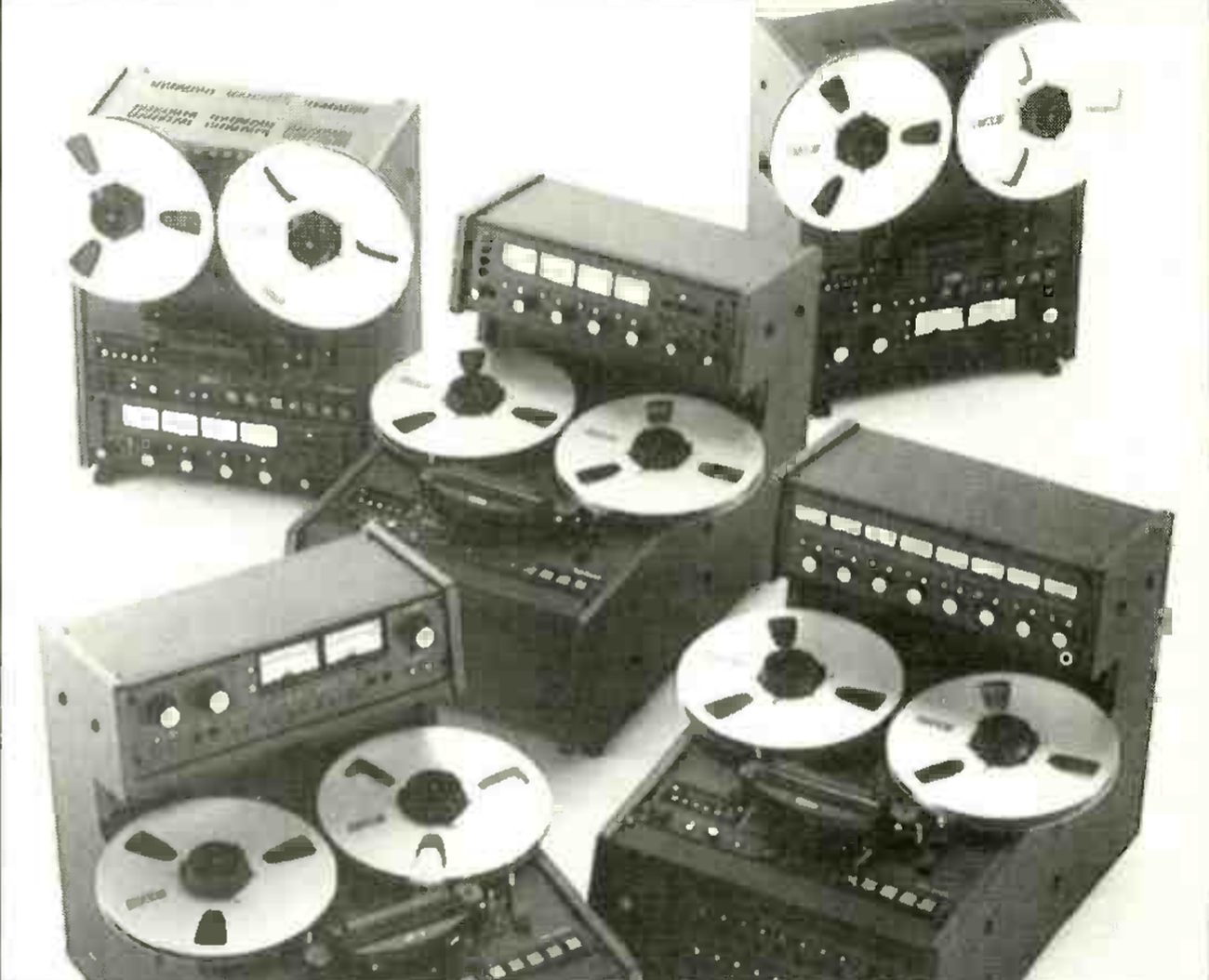 Five machines of the range grouped together: at the back, two upright transports with ten-and-a-half-inch reels, one with a pair of meters and one with a row of four; in front, three console machines with overbridge meter panels carrying two, four and eight meters.