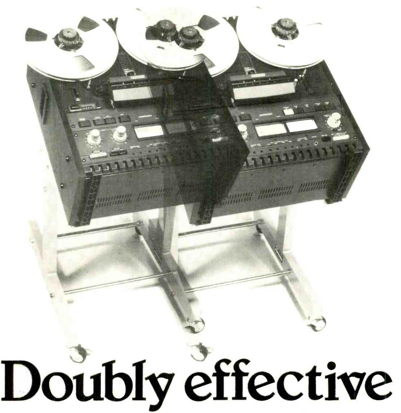 Two MX5050B recorders side by side, each mounted horizontally on a wheeled floor stand with its reels uppermost, the headline Doubly effective set beneath the stands' castors.