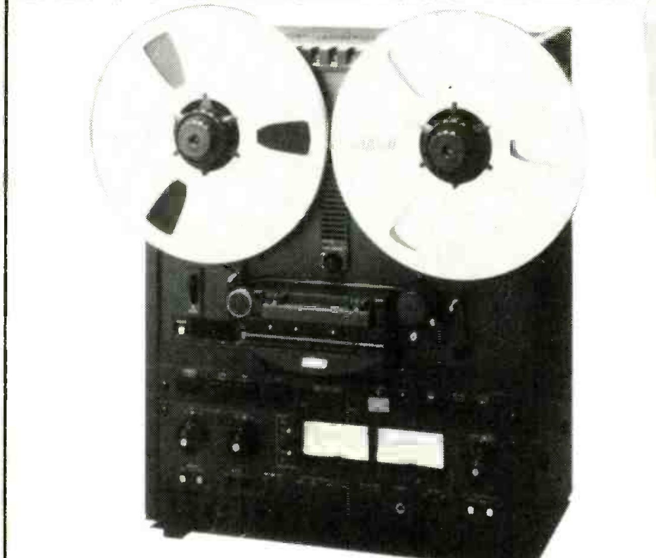 The MX5050B2II photographed from the front: two large reels on the hubs, the head assembly and transport controls beneath them, and the dark electronics panel below with two meters flanked by level knobs.