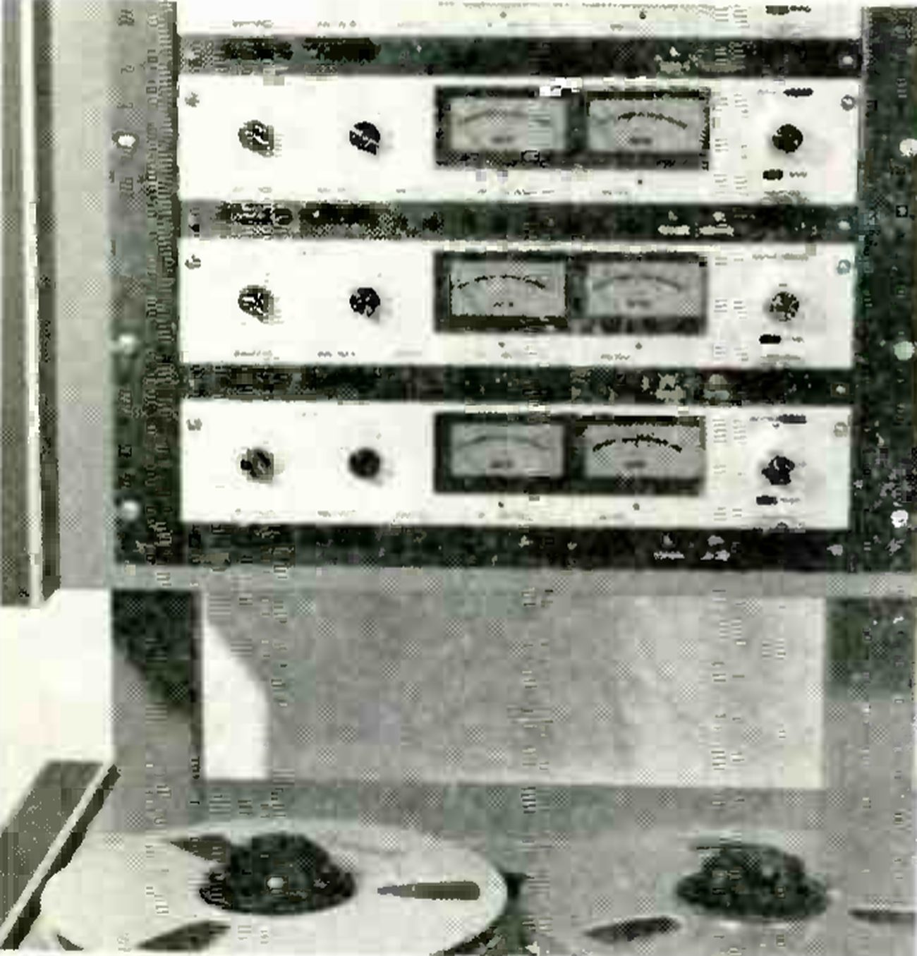 The MX5058 photographed close up: three of its rack-mounted electronics panels stacked one above another, each with a pair of VU meters and knobs either side, standing above the transport, of which only the tops of two reels show at the bottom of the frame.