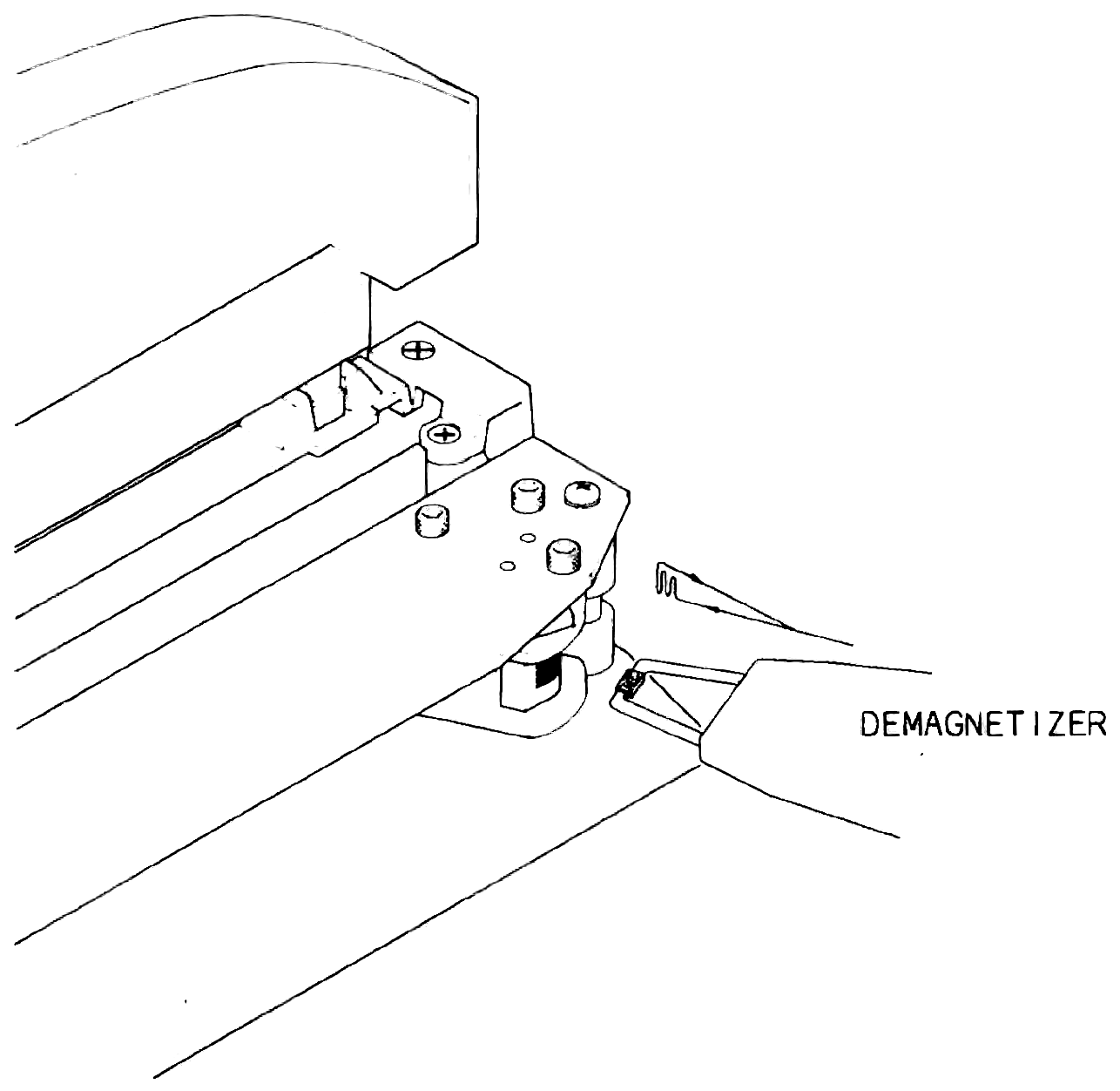 The head assembly with its cover raised and a demagnetizer held with its tips against the face of a head stack, labelled DEMAGNETIZER.