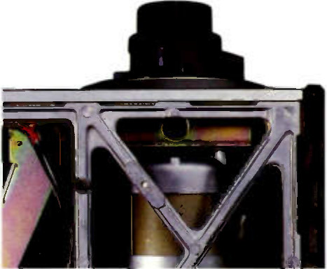 A head-on view under the transport: the machined alloy deckplate with a cast X-brace spanning the opening, the capstan motor housing rising above it and a motor can visible behind the brace.