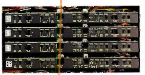 Four horizontal plug-in circuit cards stacked in a chassis, each carrying a row of trimmer adjustments and connector fingers, photographed from the front with coloured wiring visible at the edges.