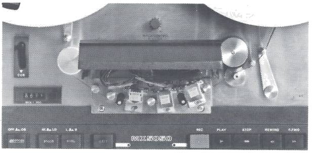 The centre of the MX-5050-8 deck with the head cover hinged up: the head stacks and their plug-in base exposed, the CUE lever and minutes-and-seconds counter to the left, the capstan and tension arm to the right, and the MX5050 push-button row below